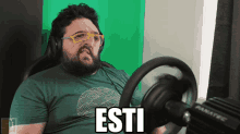 a man wearing glasses and a green shirt has the word esti on his shirt