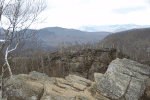 a view of a mountain range from a rocky cliff