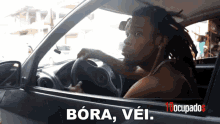 a man driving a car with bora vei written on the bottom