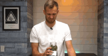 a man in a white t-shirt holds a jar with a label that says ' king of freedom ' on it