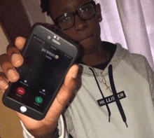 a person wearing a hollister sweatshirt holds up a cell phone