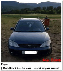 a blue ford car is parked in a field with mountains behind it