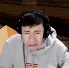 a young boy wearing headphones is crying while playing a video game .