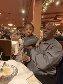 a man is holding a small child in his arms in a restaurant