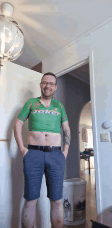 a man wearing a green joker shirt stands in a doorway