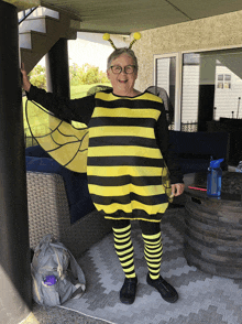 a woman in a bee costume stands on a patio