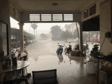 a blue scooter is parked in the rain in front of a table and chairs