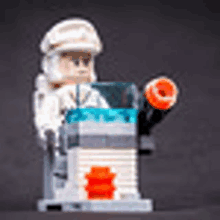 a lego star wars minifigure is sitting on a podium with a gun .