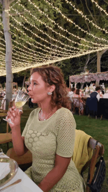 a woman in a green dress drinking from a glass