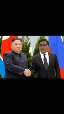 a man in a suit shakes hands with another man in front of flags