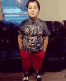 a young boy wearing a five nights at freddy 's t-shirt and red shorts