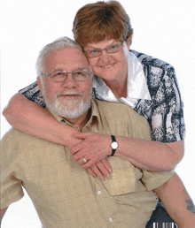 a man and woman posing for a picture with the man wearing glasses and a watch