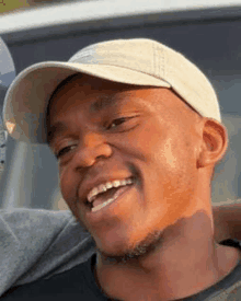 a man wearing a baseball cap is smiling and looking at the camera .