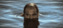 a bald man with a beard is swimming in a lake