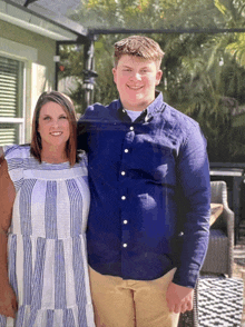 a man in a blue shirt is standing next to a woman in a white dress