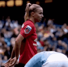 a woman in a red soccer jersey is standing next to a man in a blue shirt on a soccer field .