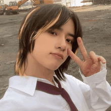 a young man wearing a white shirt and tie is giving a peace sign