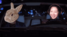 a woman wearing headphones is driving a car next to a rabbit head