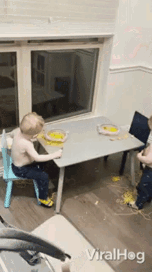 two young boys are sitting at a table with plates of food and the word viralhog on the bottom right