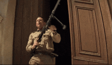 a man in a military uniform holds a gun in front of a wooden door