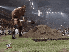 a wrestler is digging in the dirt in front of a crowd with a sign that says smack down in the background