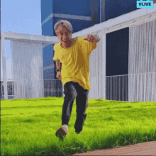 a man in a yellow shirt is jumping in the air in a field .