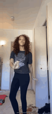 a woman with curly hair is wearing a t-shirt with a rose on it and black leggings