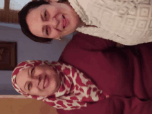 two women are posing for a picture and one is wearing a red and white scarf