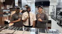 two men and a woman are standing in a kitchen holding a lollipop that says mcdonalds on it