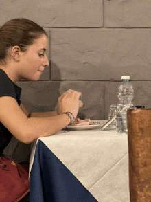 a woman sits at a table with a bottle of water