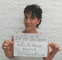 a woman holds a sign that says #por un buen trato al adulto mayor