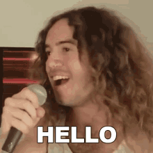 a man with long curly hair singing into a microphone with the word hello written on the bottom