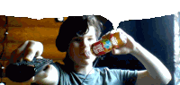 a boy is drinking a bottle of fresh bar while holding a remote