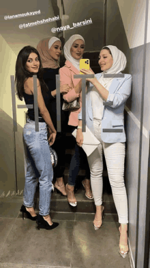 a group of women are posing for a picture and one of them is taking a picture with her phone