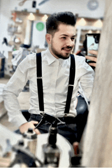 a man wearing suspenders is taking a picture of himself