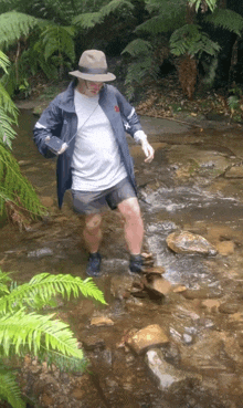 a man in a hat is crossing a stream of water