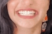 a close up of a woman 's mouth with her teeth showing and earrings .