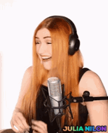 a woman with long red hair wearing headphones and a microphone is laughing .