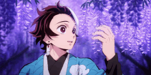 a boy in a blue kimono is looking at a purple flower .