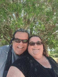 a man and a woman are posing for a picture with a tree in the background