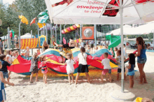 a group of children are playing in the sand under an umbrella that says ' osvezenje te ceka ' on it