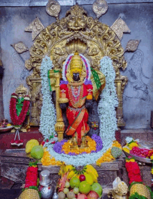 a statue of a goddess is surrounded by fruits and flowers in a temple