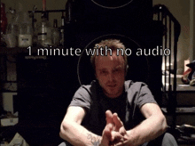 a man sits in a dark room with the words 1 minute with no audio behind him