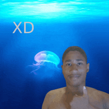 a shirtless man giving a thumbs up in front of a jellyfish and the word xd