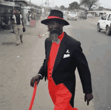 a man in a black suit and red pants is smoking a pipe