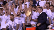 a group of soccer players holding a trophy in front of a crowd that is wearing shirts that say cup das