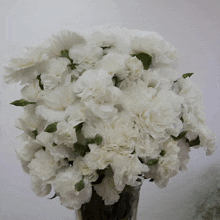 a vase filled with lots of white flowers on a table