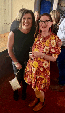 a woman in a floral dress stands next to another woman in a black top