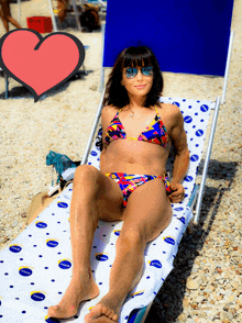 a woman in a bikini sits on a beach chair with a nivea towel on it