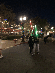 a couple of people walking down the street with lightsabers